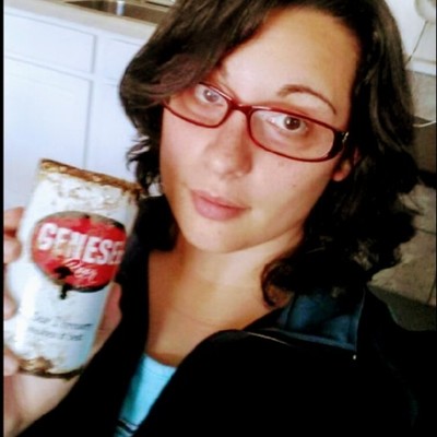 Sarah Baughman, a white women with long dark hair and glasses, holding a beer can