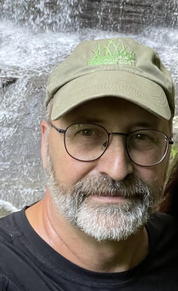 Dave Gilbert, a white man with glasses and a beard, who is wearing a hat